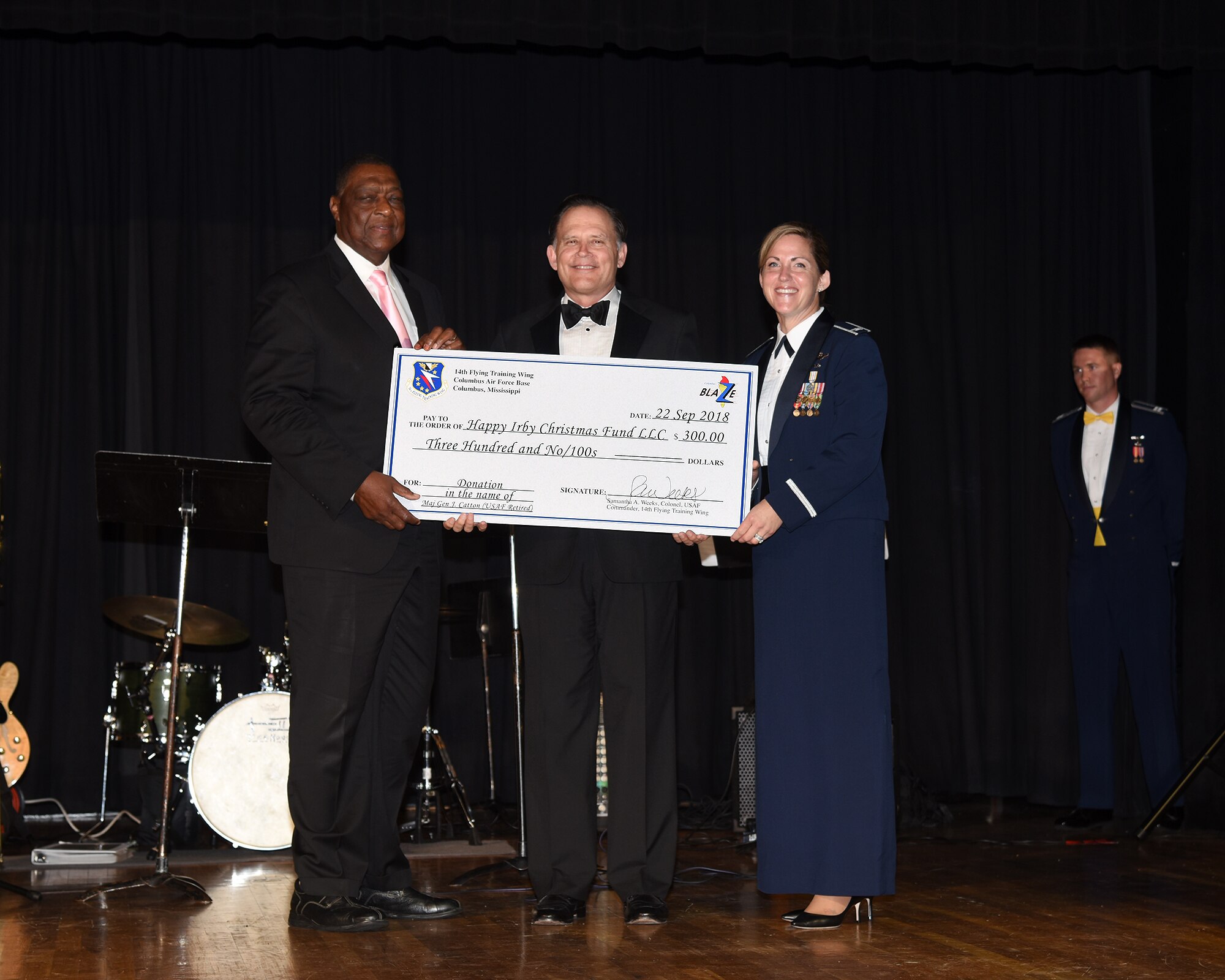 George Irby, director of Federal Programs for the city of Columbus, retired Maj. Gen. Jack Catton Jr., guest speaker and former 14th Flying Training Week commander, and Col. Samantha Weeks, current 14th FTW commander, hold a check written to the Happy Irby Christmas Fund during the 2018 Air Force Birthday Ball Sept. 22, 2018, in Columbus, Mississippi. In 2016, the Happy Irby Christmas Fund has provided clothing and supplies to over 450 children in the local community. (U.S. Air Force photo by Sharon Ybarra)