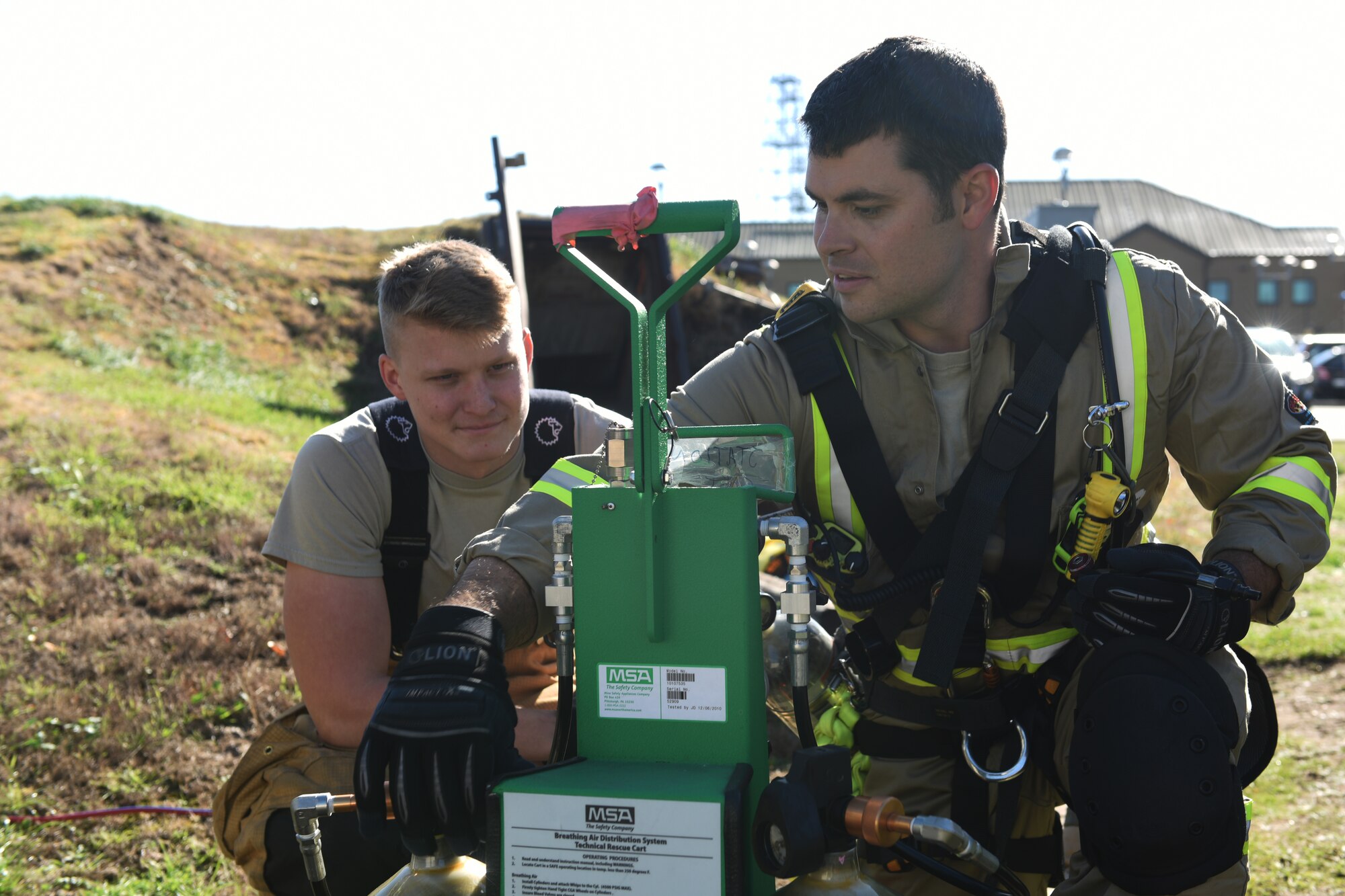 48th Civil Engineer Squadron firefighters adjust oxygen tank levels during a confined space training exercise Royal Air force Lakenheath, England, Sept. 24. Ventilation hoses provide air and exhaust toxic vapors during rescue to help patients and protect responders. (U.S. Air Force photo/ Christopher S. Sparks)