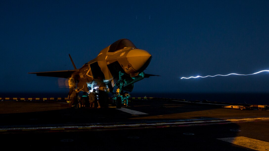 U.S. Marines with Marine Fighter Attack Squadron 211, 13th Marine Expeditionary Unit, load ordnance into an F-35B Lightning II aboard the Wasp-class amphibious assault ship USS Essex in preparation for the F-35B's first combat strike, Sept. 27, 2018. The Essex is the flagship for the Essex Amphibious Ready Group and, with the embarked 13th MEU, is deployed to the U.S. 5th Fleet area of operations in support of naval operations to ensure maritime stability and security in the Central Region, connecting the Mediterranean and the Pacific through the western Indian Ocean and three strategic choke points.
