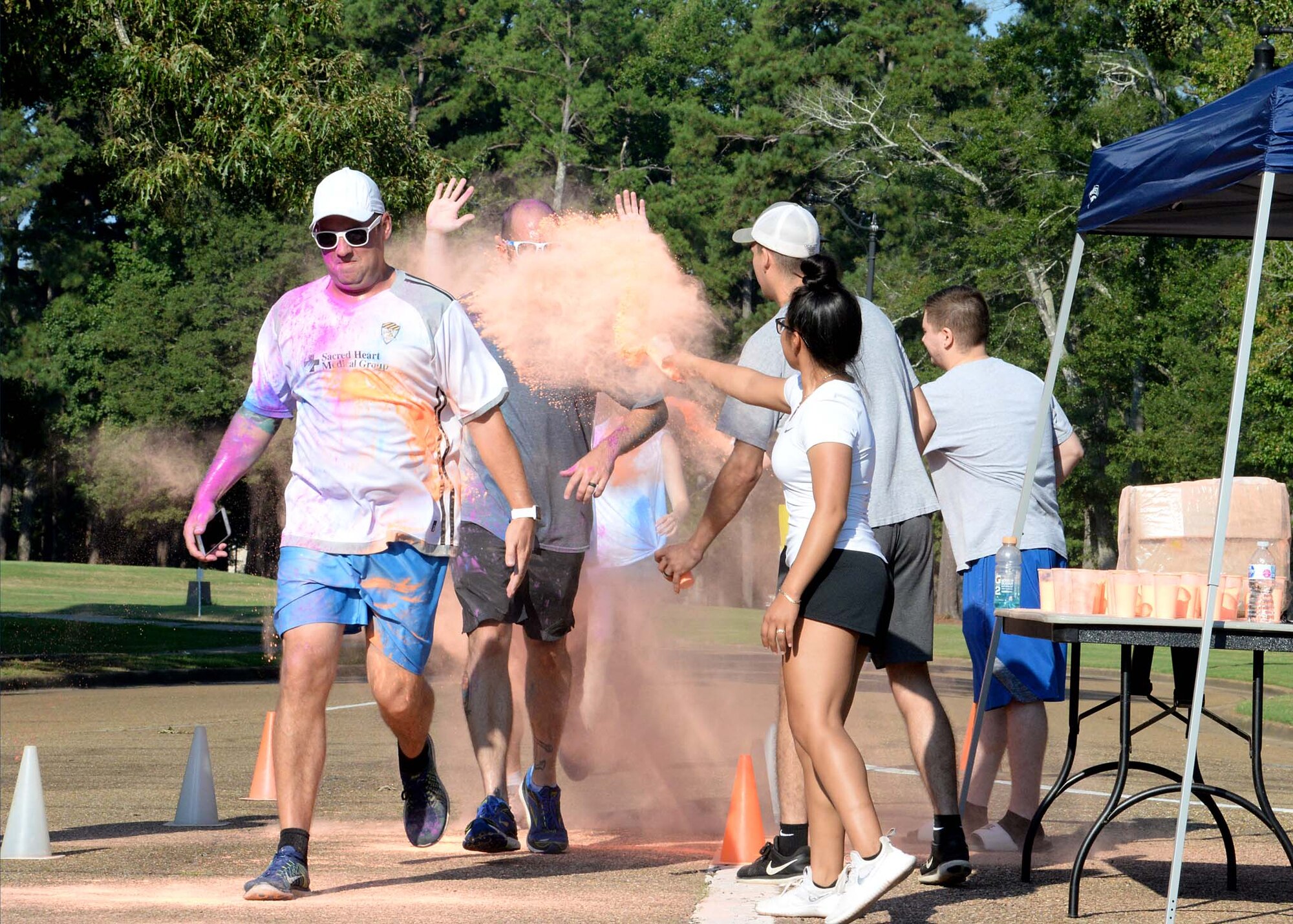 Participants run through a cloud of chalk during the sixth annual Color Run Sept. 22, 2018, at Columbus Air Force Base, Mississippi. Over 150 people participated in the run hosted by the 14th Force Support Squadron Youth Center.  (U.S. Air Force photo by Airman Hannah Bean)