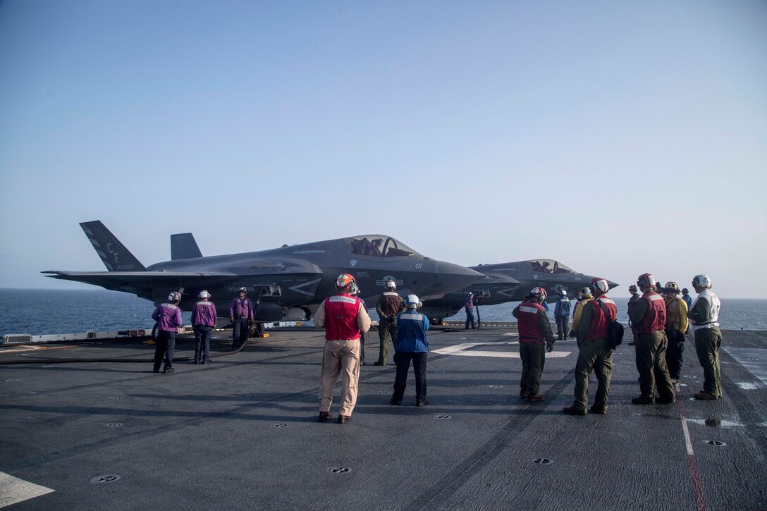 U.S. Marines and Sailors with the Essex Amphibious Ready Group (ARG) and the 13th Marine Expeditionary Unit (MEU) wait for flight operations to begin while F-35B Lightning IIs with Marine Fighter Attack Squadron 211, 13th MEU, are refueled in preparation for the F-35B's first combat strike, Sept. 27, 2018. The Essex is the flagship for the Essex Amphibious Ready Group and, with the embarked 13th MEU, is deployed to the U.S. Fifth Fleet area of operations in support of naval operations to ensure maritime stability and security in the Central Region, connecting the Mediterranean and the Pacific through the western Indian Ocean and three strategic choke points. (U.S. Marine Corps photo by Cpl. Francisco J. Diaz Jr./Released)