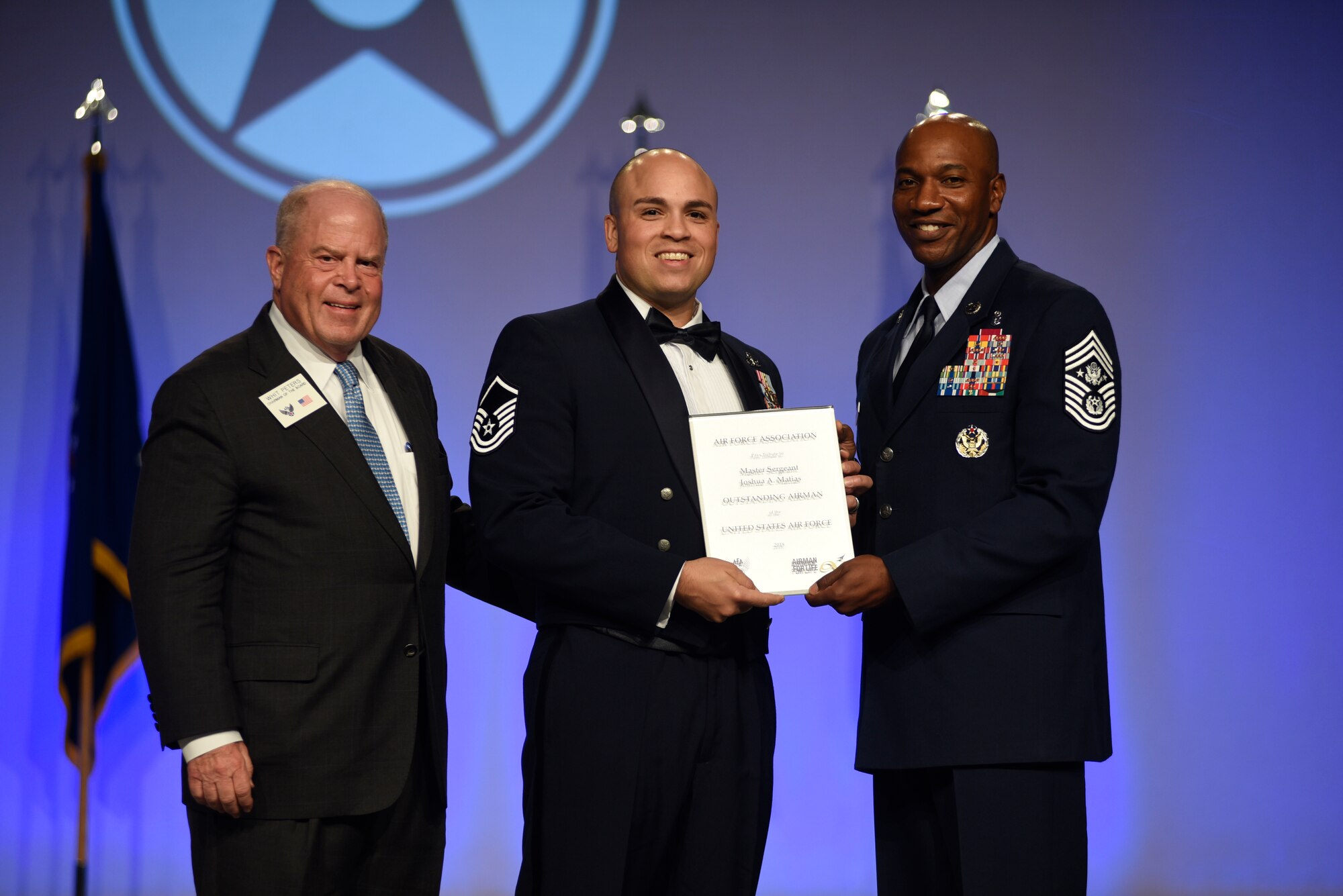 Master Sgt. Josh Matias, 14th Operations Group tower chief air traffic controller, is recognized by Whit Peters, Air Force Association Chairman of the Board, and Chief Master Sgt. of the Air Force Kaleth O. Wright, during the 2018 Air Force Association Air, Space and Cyber Conference from Sept. 17 in National Harbor, Maryland. (Photo by Mike Tsukamoto, Air Force Magazine)