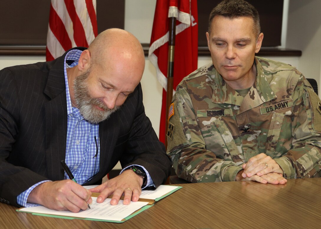 Tulsa District Commander, Col. Christopher A. Hussin watches as Tulsa County Levee Commissioner, Todd Kilpatrick signs the Feasibility Study Cost Sharing Agreement between the Tulsa District and the U.S. Army Corps of Engineers. The federal government has allocated $3 million to fund the total cost of the two year study, which will help the Corps of Engineers identify flood risk reduction solutions for the levee system.