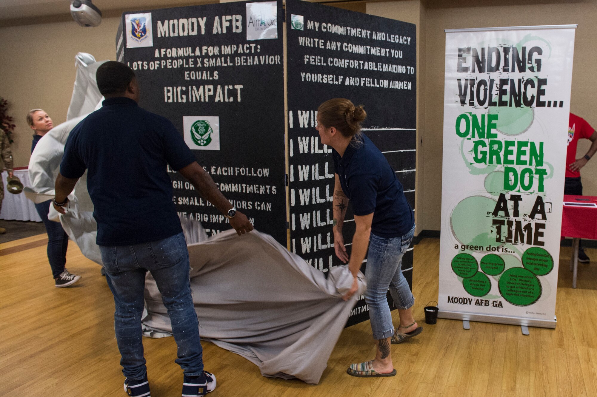 Green Dot trainers unveil the Green Dot Commitment Board during the Comprehensive Airmen and Fitness Day, Sept. 28, 2018, at Moody Air Force Base, Ga. The board was crafted for Airmen and by Airmen and will travel across the base and Airmen will write down their commitments. Green Dot is an Air Force program designed to reinforce the key principles of prevention that can be applied to many issues such as sexual assault, suicide prevention, domestic violence, stalking and child abuse prevention.