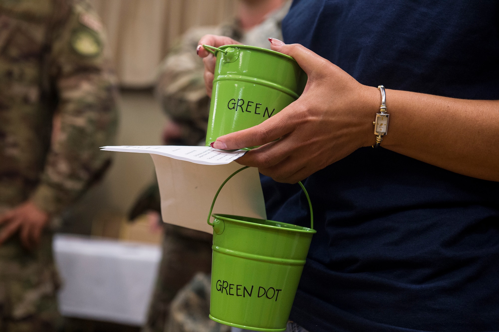 Gladys Colon, 23d Wing violence prevention integrator, holds Green Dot buckets with chalk during the unveiling of the Green Dot Commitment Board, Sept. 28, 2018, at Moody Air Force Base, Ga. Airmen crafted the board to allow Team Moody to share their personal stories and write commitments. Green Dot is an Air Force program designed to reinforce the key principles of prevention that can be applied to many issues such as sexual assault, suicide prevention, domestic violence, stalking and child abuse prevention.