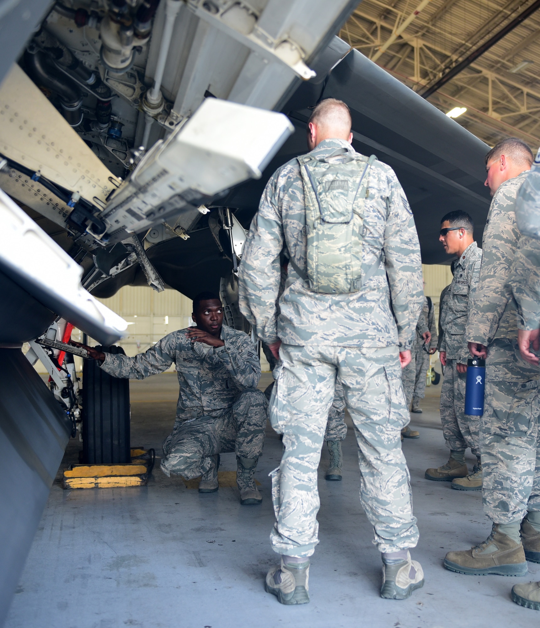 Airmen examine the operations of an F-22 Raptor munitons hull.