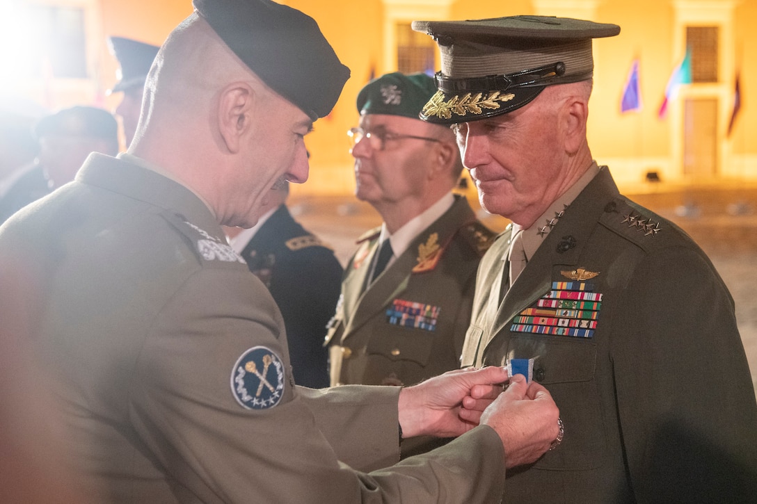A Polish military official affixes a medal to the uniform of Marine Corps Gen. Joe Dunford, chairman of the Joint Chiefs of Staff.