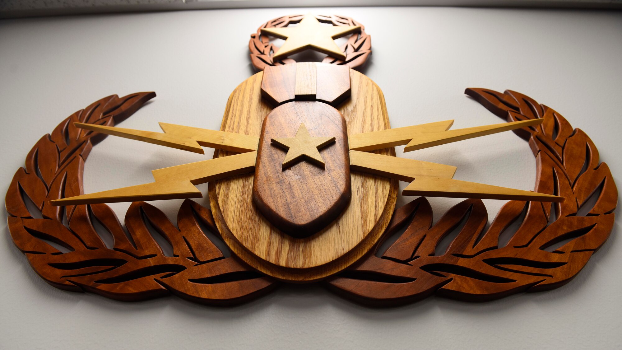 The Explosive Ordinace Disposal team official badge insigina is displayed on the wall inside the 92nd Civil Engineer Squadron EOD team classroom at Fairchild Air Force Base, Washington, Sept. 28, 2018. EOD Airmen apply classified techniques and speecal procedures to lessen or totally remove the hazards created by the presence of unexploded ordinance. (U.S. Air Force photo/Airman 1st Class Lawrence Sena)