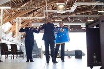 Maj. Gen. Patrick Doherty, (right) 19th Air Force commander, Maj. Gen. Andrew Croft, (middle) 12th Air Force commander, and Chief Master Sergeant Sarah Esparza, (left) 49th Wing command chief, unfurl the new 19th Air Force flag during a major command reassignment ceremony Sept. 28, on Holloman Air Force Base, N.M. Transistioning to Air Education and Training Command from Air Combat Command will allow the 49th Wing to more effectively execute their mission of training future F-16 Viper and MQ-9 Reaper pilots and sensor operators. (U.S. Air Force photo by Tech. Sgt Amanda N. Junk)