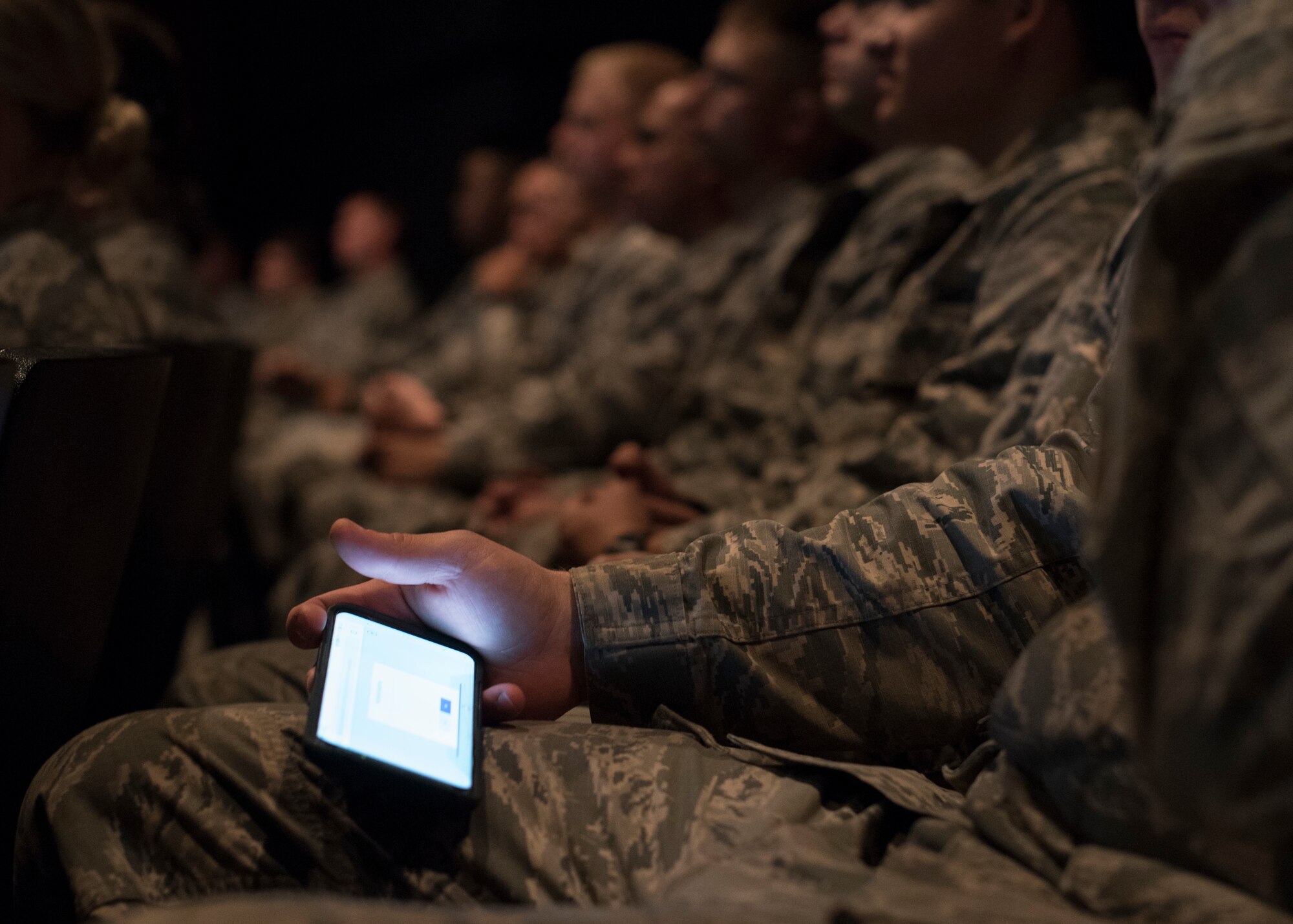 Airmen attending a base all-call use their smart phones to follow along and interact during the presentation at Fairchild Air Force Base, Washington, Sept. 26, 2018. Fairchild leadership supporting Airmen is a high priority, and were testing out the interactive format as a means to better connect with Airmen. (U.S. Air Force photo/Senior Airman Ryan Lackey)