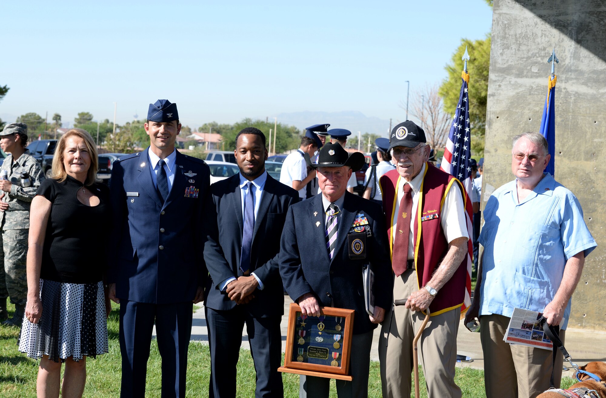 Attendees of the Prisoner of War/Missing in Action ceremony stand for a picture at Freedom Park on Nellis Air Force Base, Nev., Sept. 21, 2018. Newt Hiesley used his son, who was medically discharged from the military, as the man on the flag. (U.S. Air Force photo by Airman 1st Class Bryan T. Guthrie)