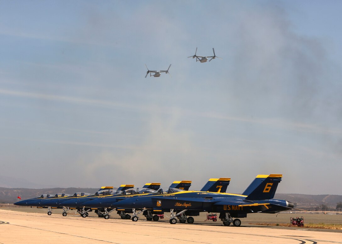MV-22B Osprey with Marine Medium Tiltrotor Squadron 161, Marine Aircraft Group 16, 3rd Marine Aircraft Wing fly over U.S. Navy Blue Angels during the Marine Air-Ground Task Force Demonstration at the Marine Corps Air Station (MCAS) Miramar Air Show September 28, 2018 Miramar, California.  This year's air show honors "100 years of women in the Marine Corps" by featuring several performances and displays that highlight accomplishments and milestones women made since the first female enlistee, Opha May Johnson, who joined the service in 1918.  (U.S. Marine Corps photo by Cpl. Joshua S. McAlpine)