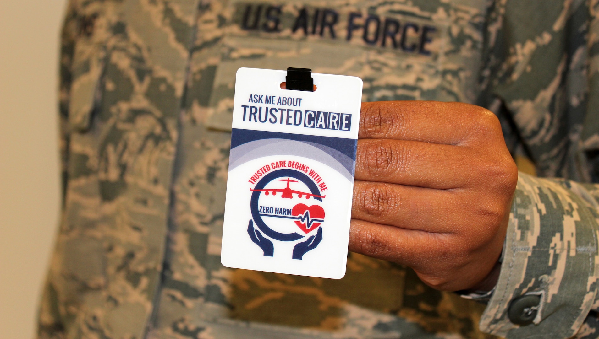 An Airman holds up his Trusted Care badge at the Defense Health Headquarters.