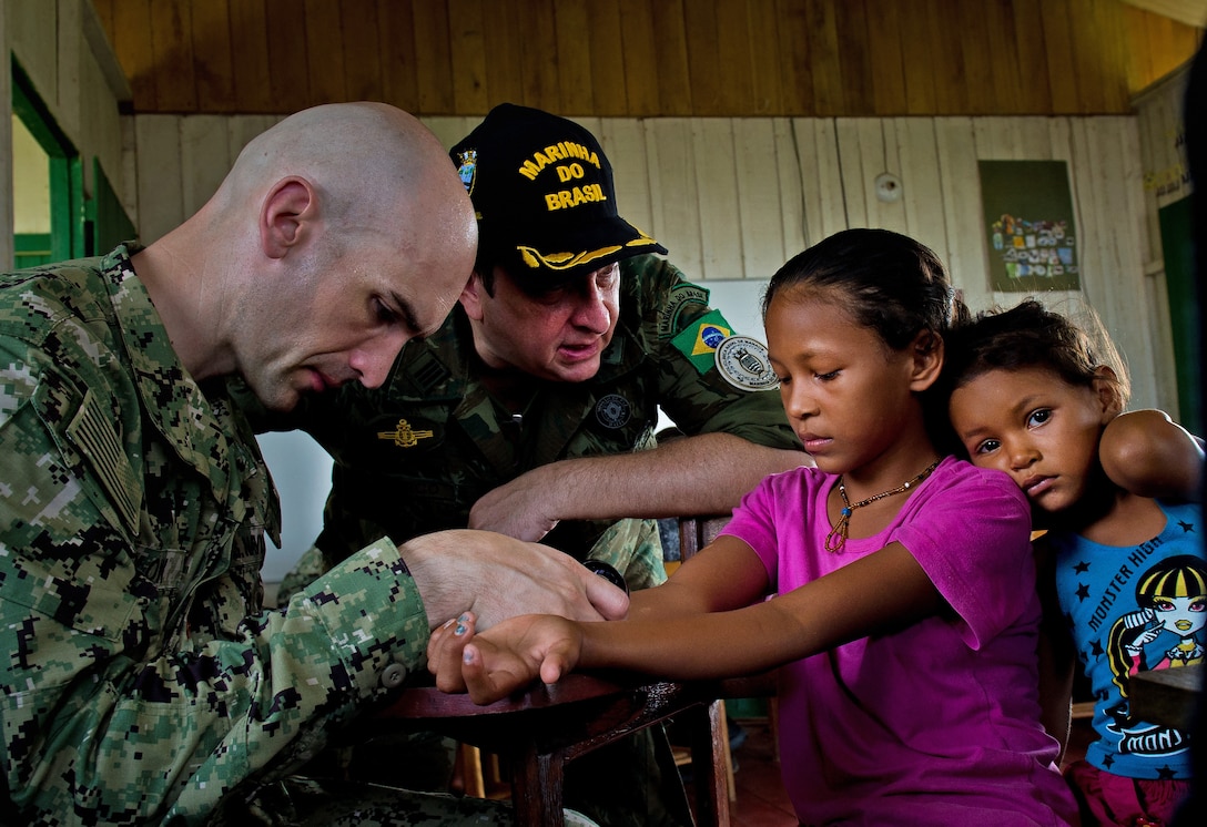 Navy Lt. Cmdr. Thomas Barlow examines a child's hand.