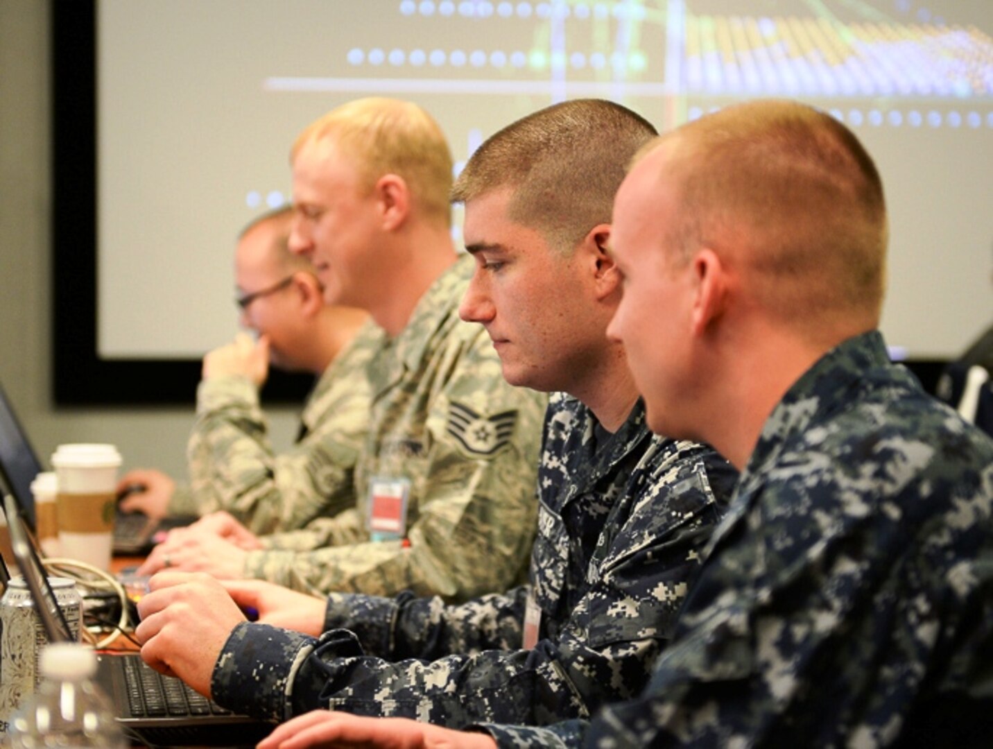 Candid photograph of four CDX military participants concentrating at computers
