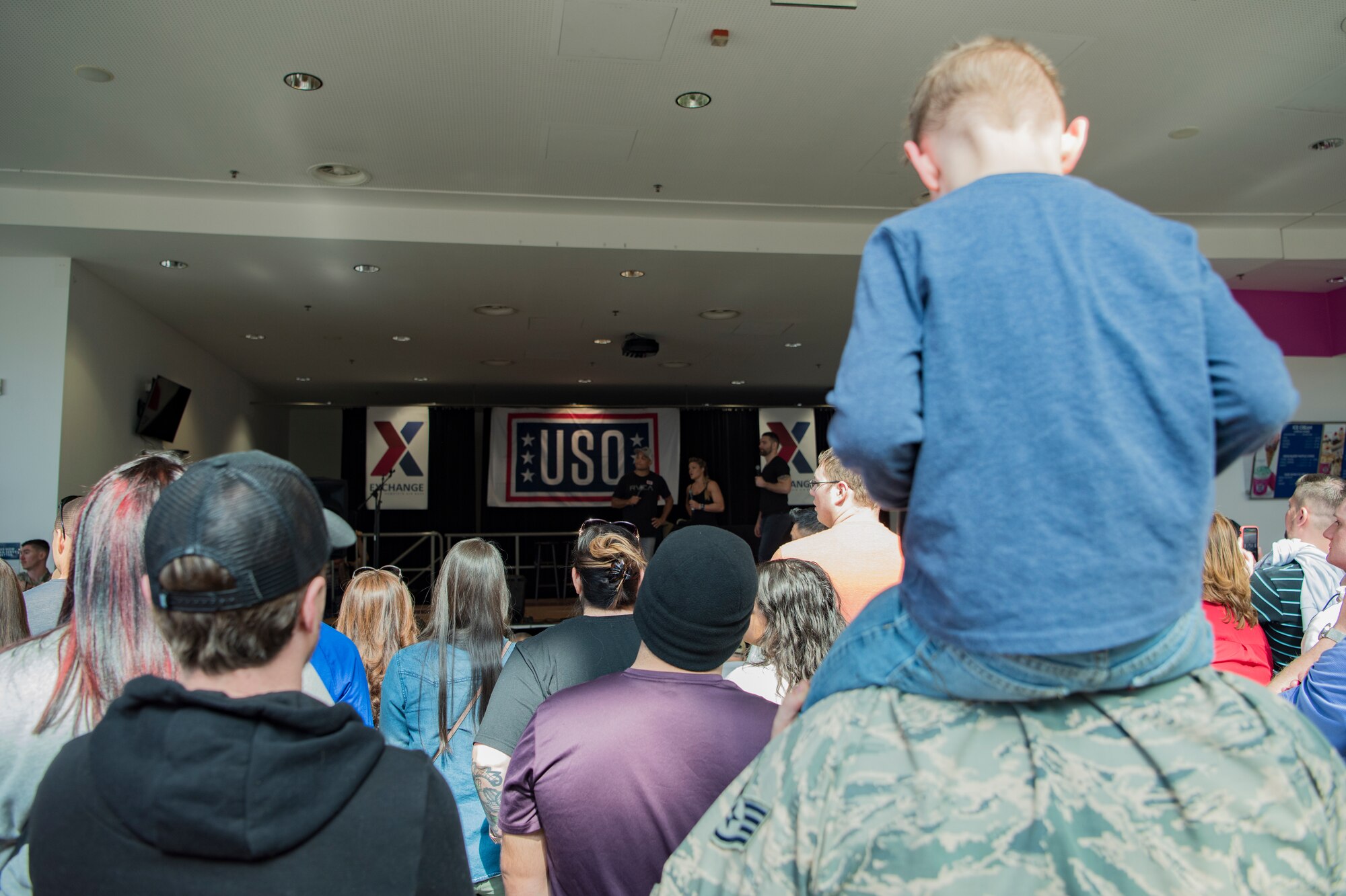 A U.S. Air Force Staff Sgt. and his son gathered with other members of the audience for the USO Spring Visit tour on Ramstein Air Base, Germany, March 30, 2019.