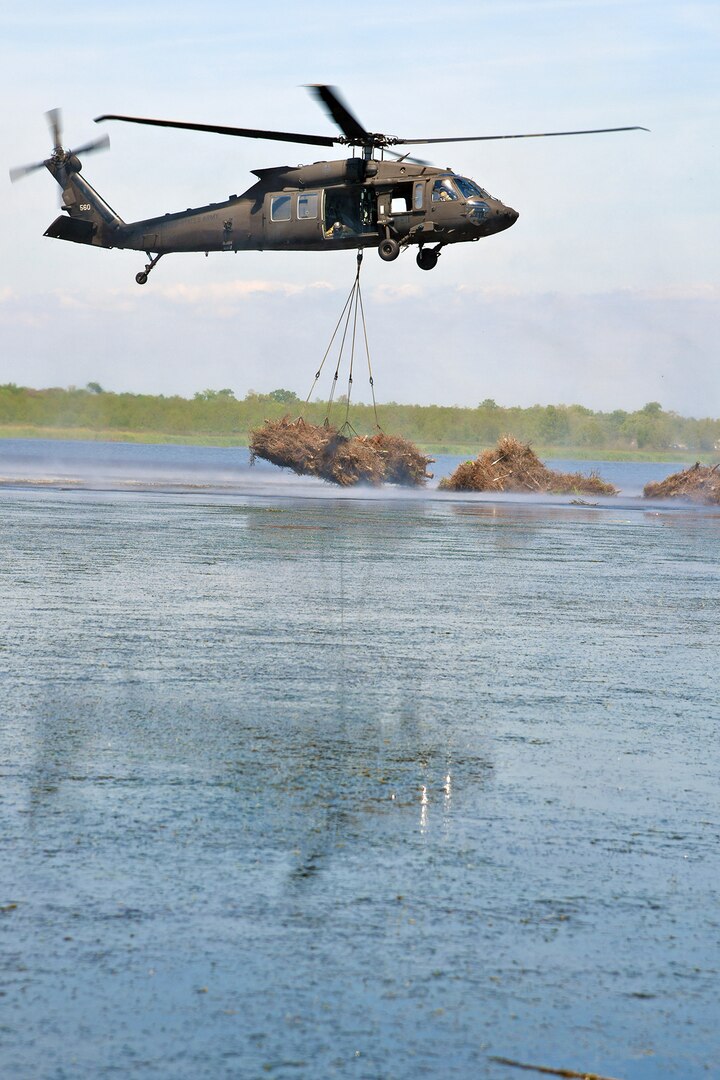 A Louisiana National Guard UH-60 Black Hawk drops a load of Christmas trees to help slow coastal erosion in Bayou Sauvage in New Orleans, March 28, 2019.