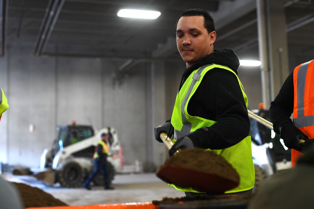 Senior Airman Ray Brigante, 319th Civil Engineer Squadron operations management journeyman, shovels sand into a funnel during a sandbag stockpile volunteer event March 28, 2019, in Grand Forks, North Dakota. Base members and local firefighters were among the volunteers who worked together to help create 10,000 sandbags for the city of Grand Forks in preparation for an expected flood in the spring. (U.S. Air Force photo by Senior Airman Elora J. Martinez)