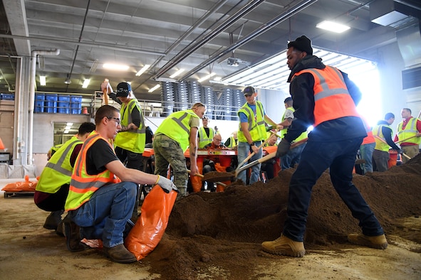 Tech. Sgt. Travis Sanford, 319th Operations Support Squadron air traffic control senior watch supervisor, right, shovels sand into a bag held open by Tech. Sgt. Codie Volk, 69th Maintenance Squadron aerospace ground equipment section chief, during a sandbag stockpile event March 28, 2019, in Grand Forks, North Dakota. Volunteers worked to fill several thousand sandbags out of the city’s 10,000-goal. (U.S. Air Force photo by Senior Airman Elora J. Martinez)