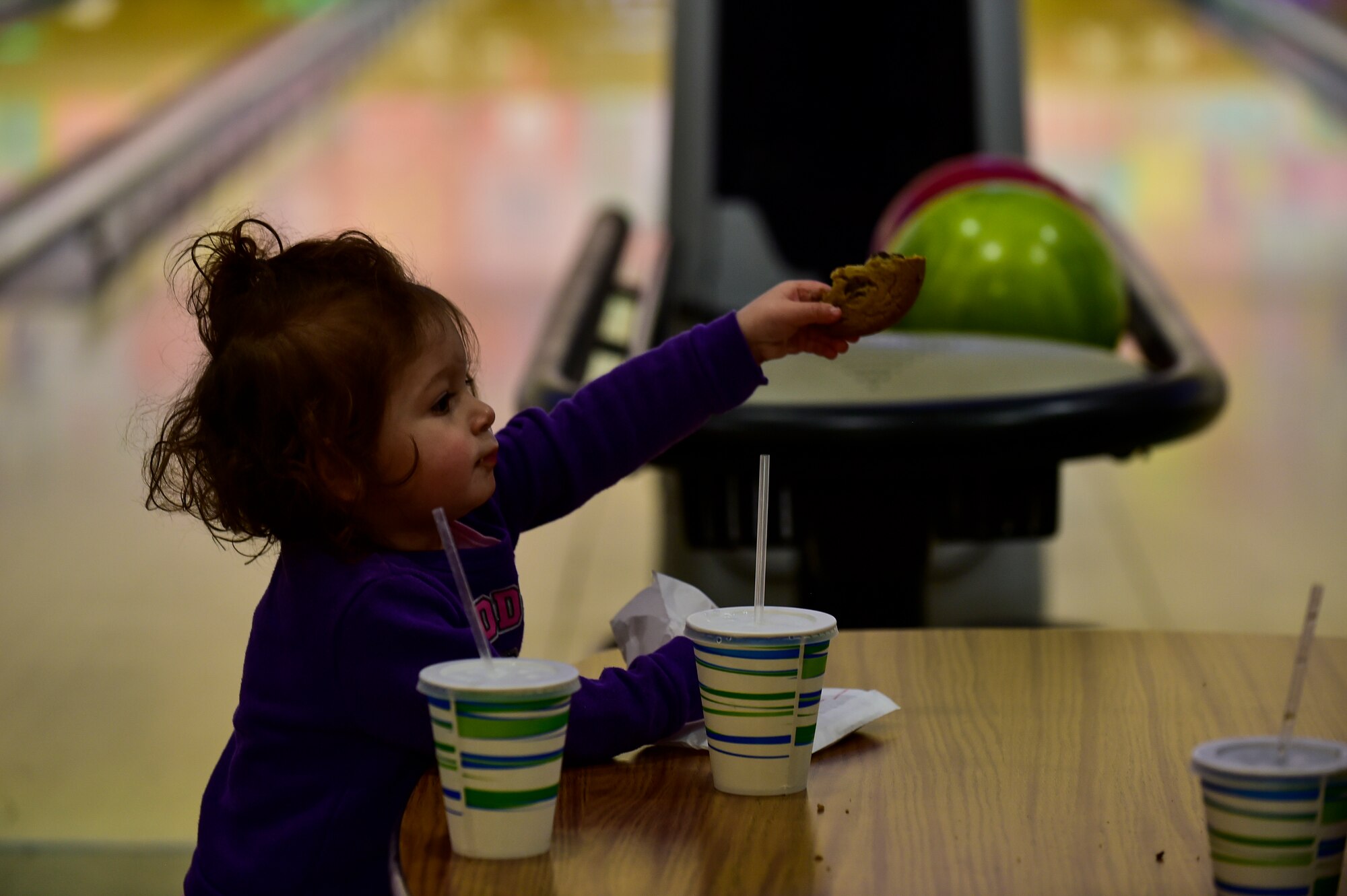 A Team Ramstein child holds a cookie in her hand during the Deployed Family Dinner at the Vogelweh Bowling Alley on Vogelweh Military Complex, Germany, March 28, 2019. The Deployed Family Dinners give families of deployed personnel a chance to meet with other families who are experiencing the same challenges caused by deployment, build friendships, and develop support networks. (U.S. Air Force photo by Staff Sgt. Jonathan Bass)