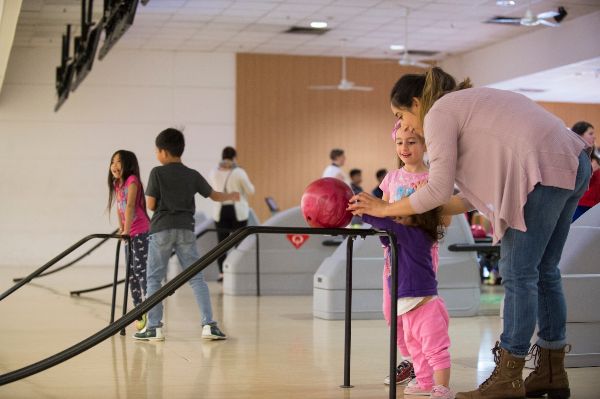 A Team Ramstein mother helps her daughter push a bowling ball down a ramp during the Deployed Family Dinner at the Vogelweh Bowling Alley on Vogelweh Military Complex, Germany, March 28, 2019. Approximately 40 family members attended the event. (U.S. Air Force photo by Staff Sgt. Jonathan Bass)