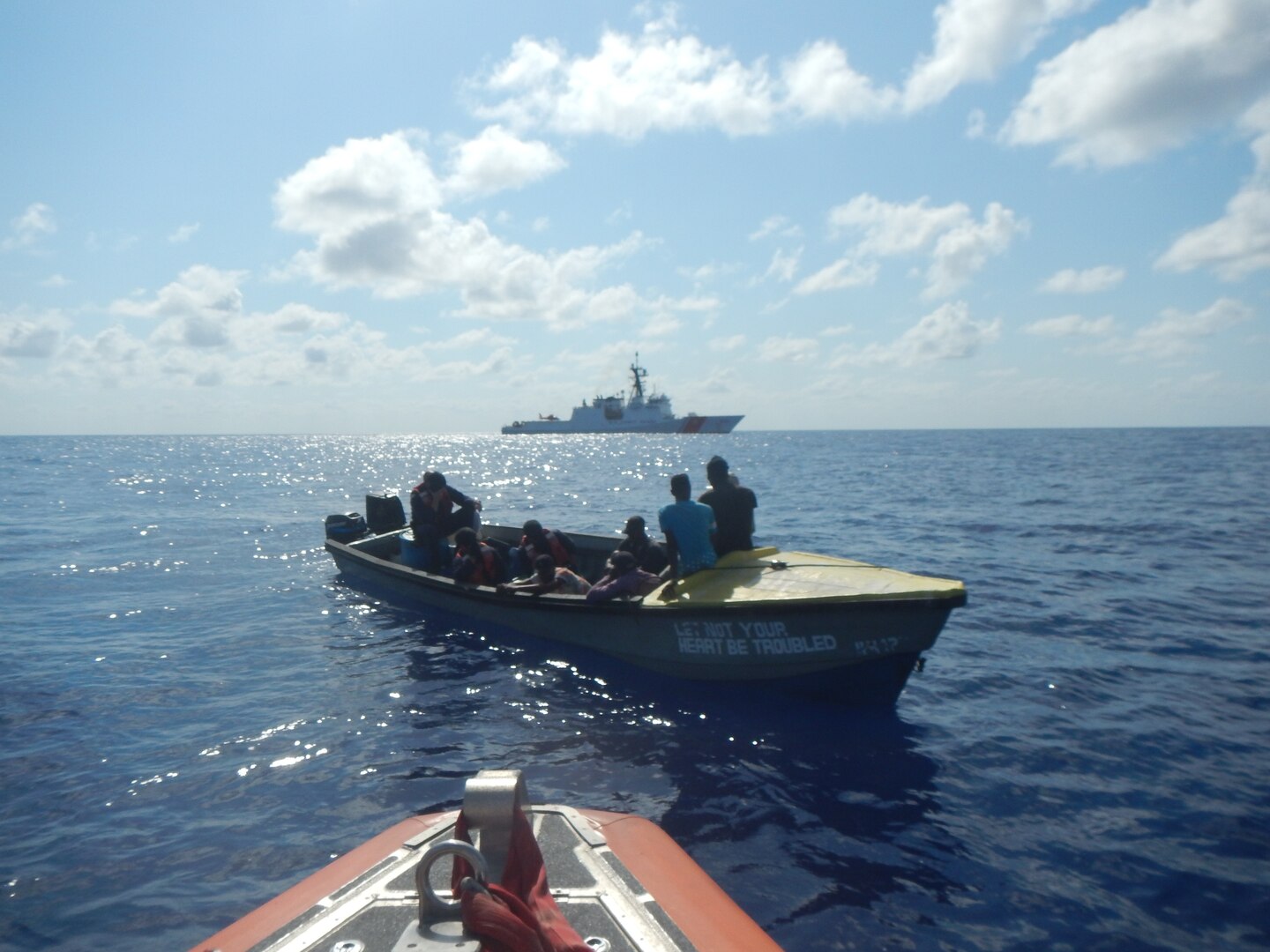 Coast Guard Cutter Hamilton small boat crew boards a suspected smuggling vessel while the Hamilton maintains security in the background March 22, 2019, in the Caribbean Sea.