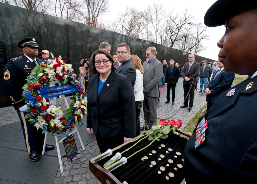 Woman looks at tray of lapel pins before a presentation ceremony.