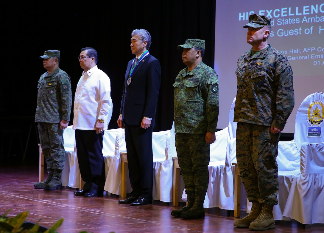 From left, Armed Forces of the Philippines Lt. Gen. Gilbert Gapay, commander, Southern Luzon Command, and Philippine Exercise Co-Director; Undersecretary Cardozo M. Luna, Undersecretary of the Department of National Defense; Sung Y. Kim, U.S. Ambassador to the Philippines; Armed Forces of the Philippines Gen. Benjamin Madrigal, Jr., AFP Chief of Staff; and U.S. Marine Brig. Gen. Christopher A. McPhillips, commanding general, 3rd Marine Expeditionary Brigade stand shoulder-to-shoulder at Tejeros Hall, Camp General Emilio Aguinaldo, Quezon City, Manila, Philippines, April 1, 2019. The ceremony represented the official commencement of Balikatan 2019 and the continued partnership between the United States and the Republic of the Philippines. Balikatan 19, in its 35th iteration, is an annual U.S.-Philippine military training focused on a variety of missions, including humanitarian assistance and disaster relief, counterterrorism, and other combined military operations held from April 1 to April 12.