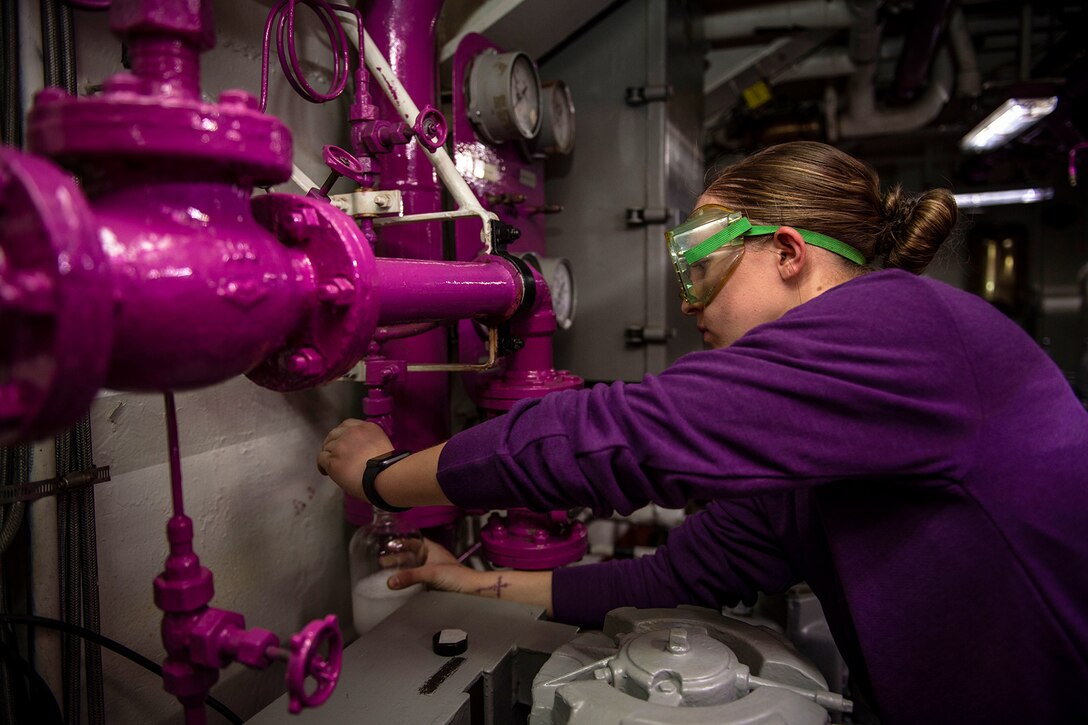 A service member performs maintenance on a ship.