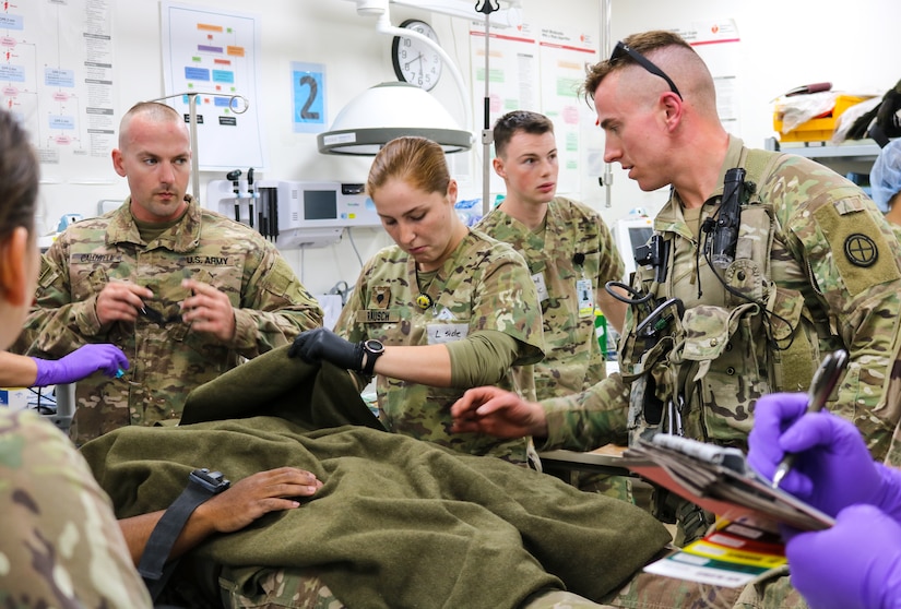 Spc. Alyson Rausch, 452d Combat Support Hospital, inspects mock casualty's injuries during the Golden Trident mass casualty training exercise at Camp Arifjan, Kuwait, March 21, 2019.