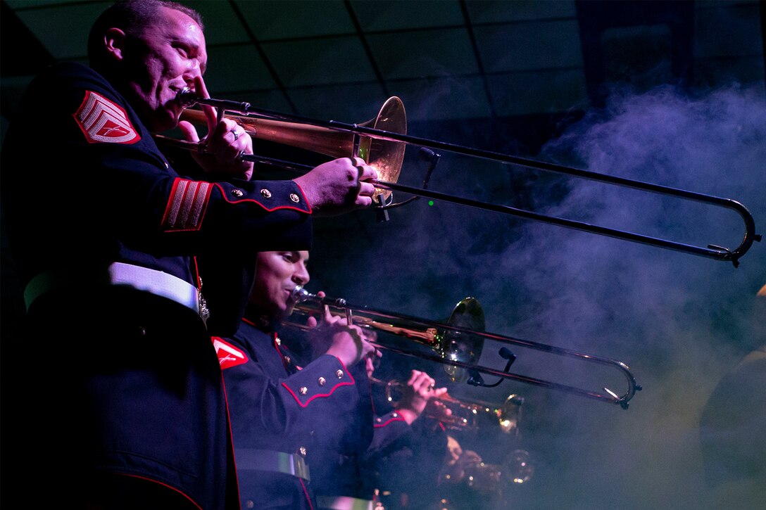 Service members in a band perform on stage.