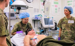 Col. Berger, 452d Combat Support Hospital, reassures a mock casualty during the Golden Trident mass casualty training exercise at Camp Arifjan, Kuwait, March 21, 2019.