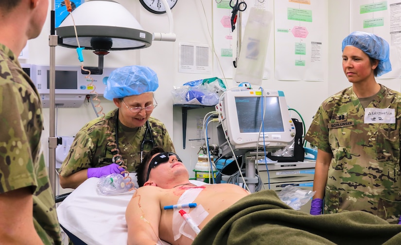 Col. Berger, 452d Combat Support Hospital, reassures a mock casualty during the Golden Trident mass casualty training exercise at Camp Arifjan, Kuwait, March 21, 2019.