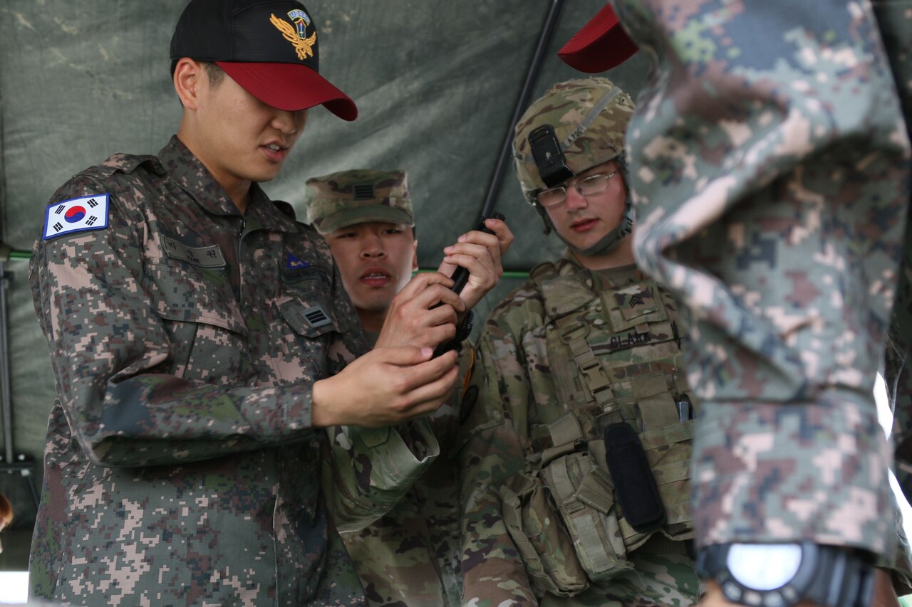 A general looks on as a South Korean soldier demonstrates a skill for an American soldier.