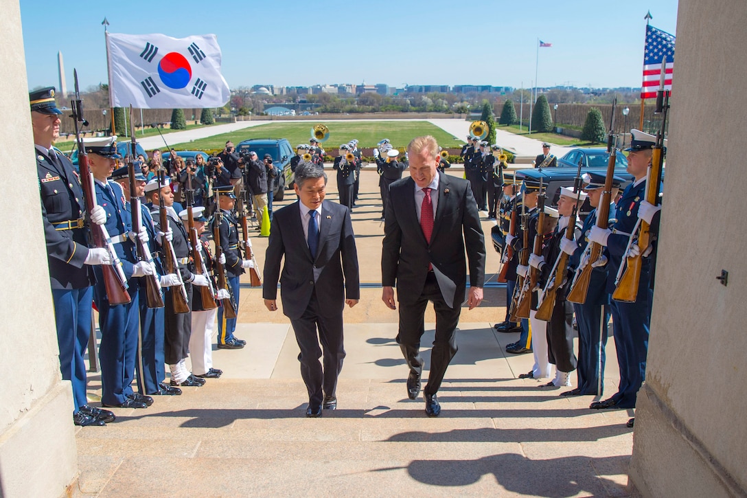 Acting Defense Secretary Patrick M. Shanahan and the South Korean defense minister walk up steps past honor guard troops.