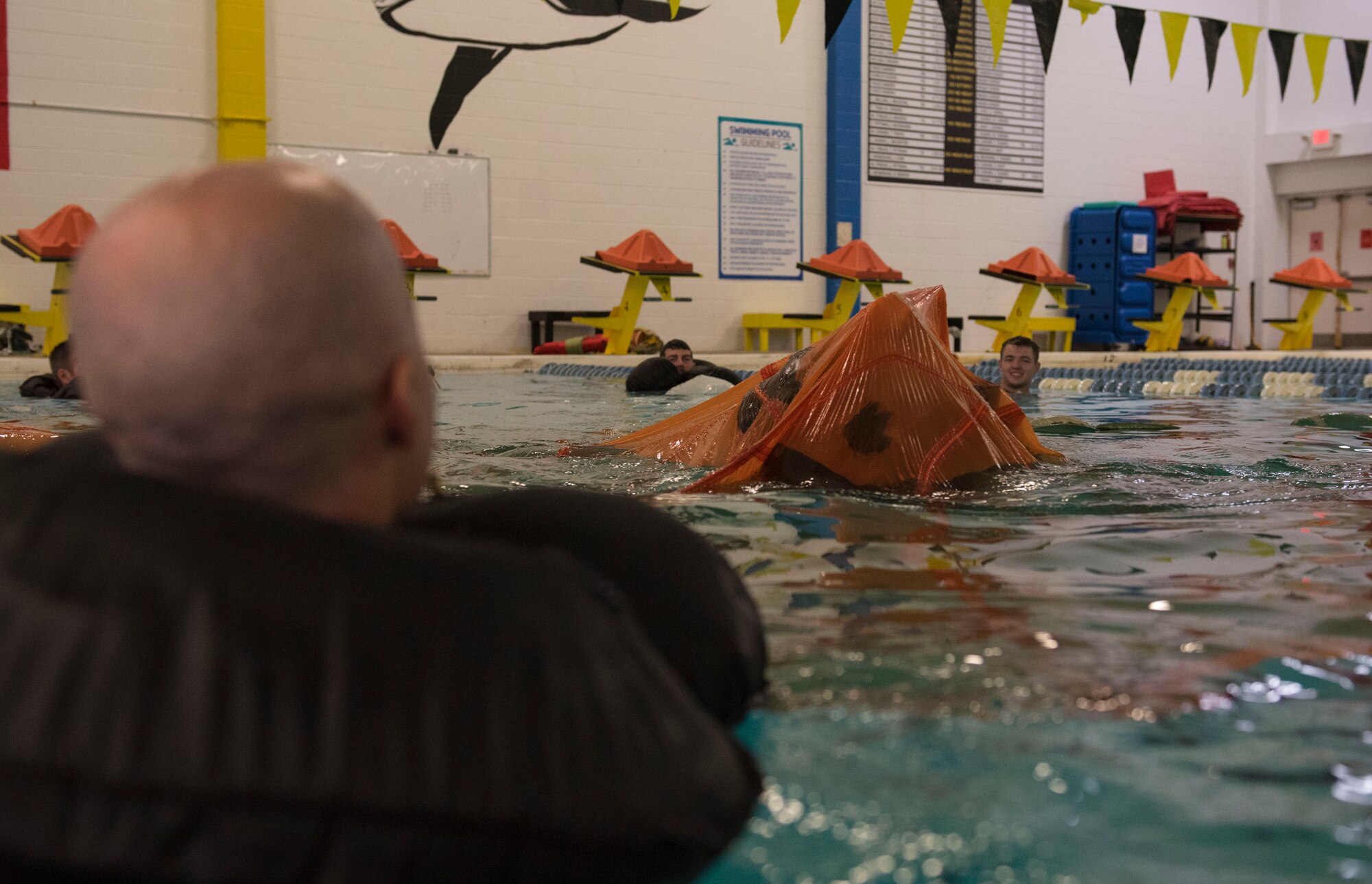 A pilot makes his way out from under a parachute during water survival training, March 26, 2019, at the Goldsboro YMCA, North Carolina. Survival, evasion, resistance and escape augmentees help conduct the training, which fortifies aircrew’s SERE skills. (U.S. Air Force photo by Senior Airman Kenneth Boyton)