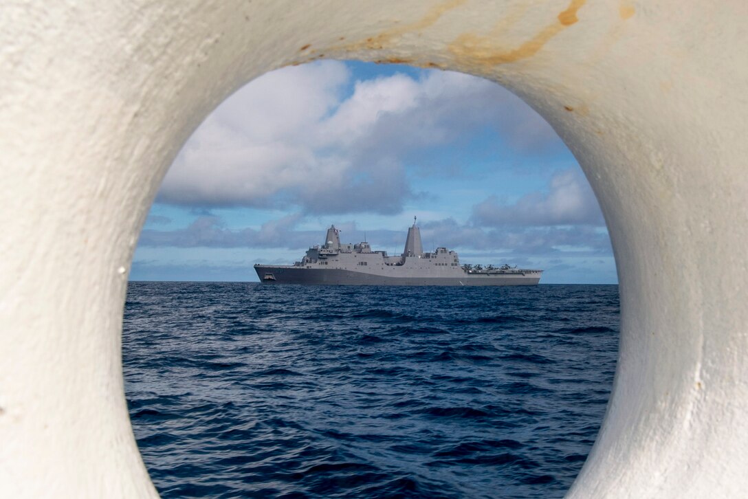 A ship traveling in the water is visible through a circular opening on another ship.