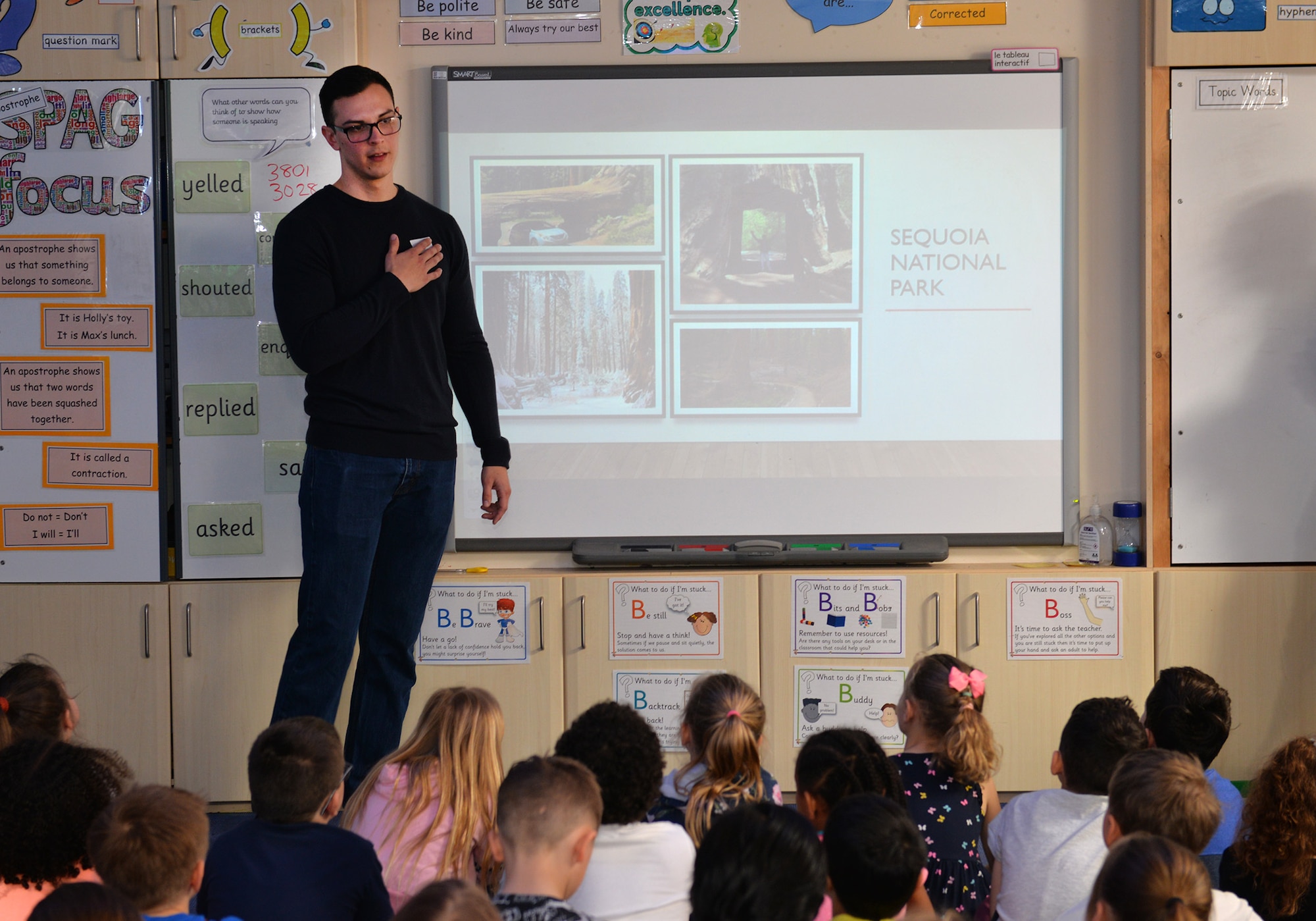 U.S. Air Force Senior Airman Alek Rodriguez-Kozlowski, 100th Civil Engineer Squadron firefighter, talks to local school children on American and British national parks during a visit to Beck Row Primary Academy, Suffolk, England, March 29, 2019. Airmen from RAF Mildenhall gave presentations and talked to students about a variety of differences between the United Kingdom and United States. Topics included animals, climates and time zones, the U.S. President and the Queen. The school children are currently learning about the United States of America and the RAF Mildenhall Airmen visited them to answer questions and give a better insight on the subject. (U.S. Air Force photo by Karen Abeyasekere)