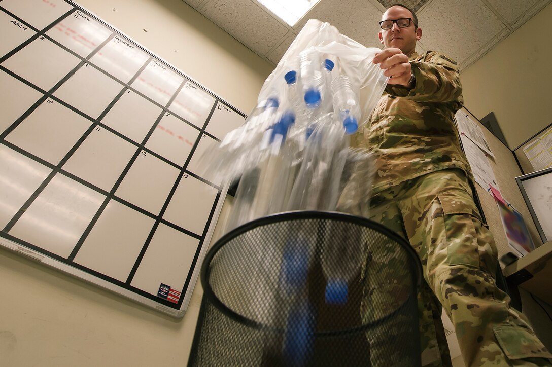 An Airman throws plastic bottles into a trash bin March 30, 2019, at Al Udeid Air Base, Qatar. Recyclable items such as glass and plastic bottles are placed in trash dumpsters on base, then sorted and recycled at locations off the installation. In addition, other used assets such as batteries and bulbs can be collected and given to host-nation partners for recycling. (U.S. Air Force illustration by Tech. Sgt. Christopher Hubenthal)