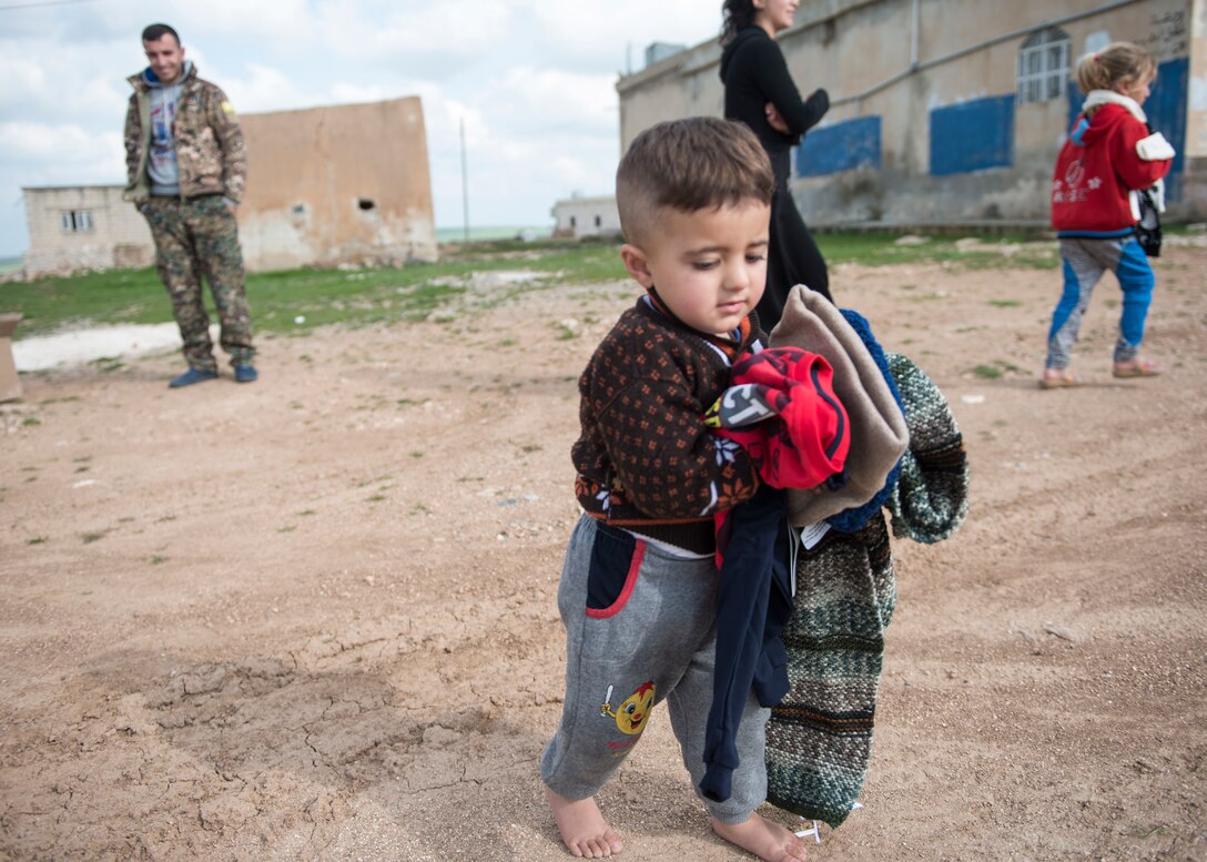 A little boy walks off with new clothes March 12, 2019, Southwest Asia. U.S. military members donated clothes, money and time to help the families in the local area that have been affected by violent extremists and conflict. (U.S. Air Force photo by Staff Sgt. Malissa Armstrong)