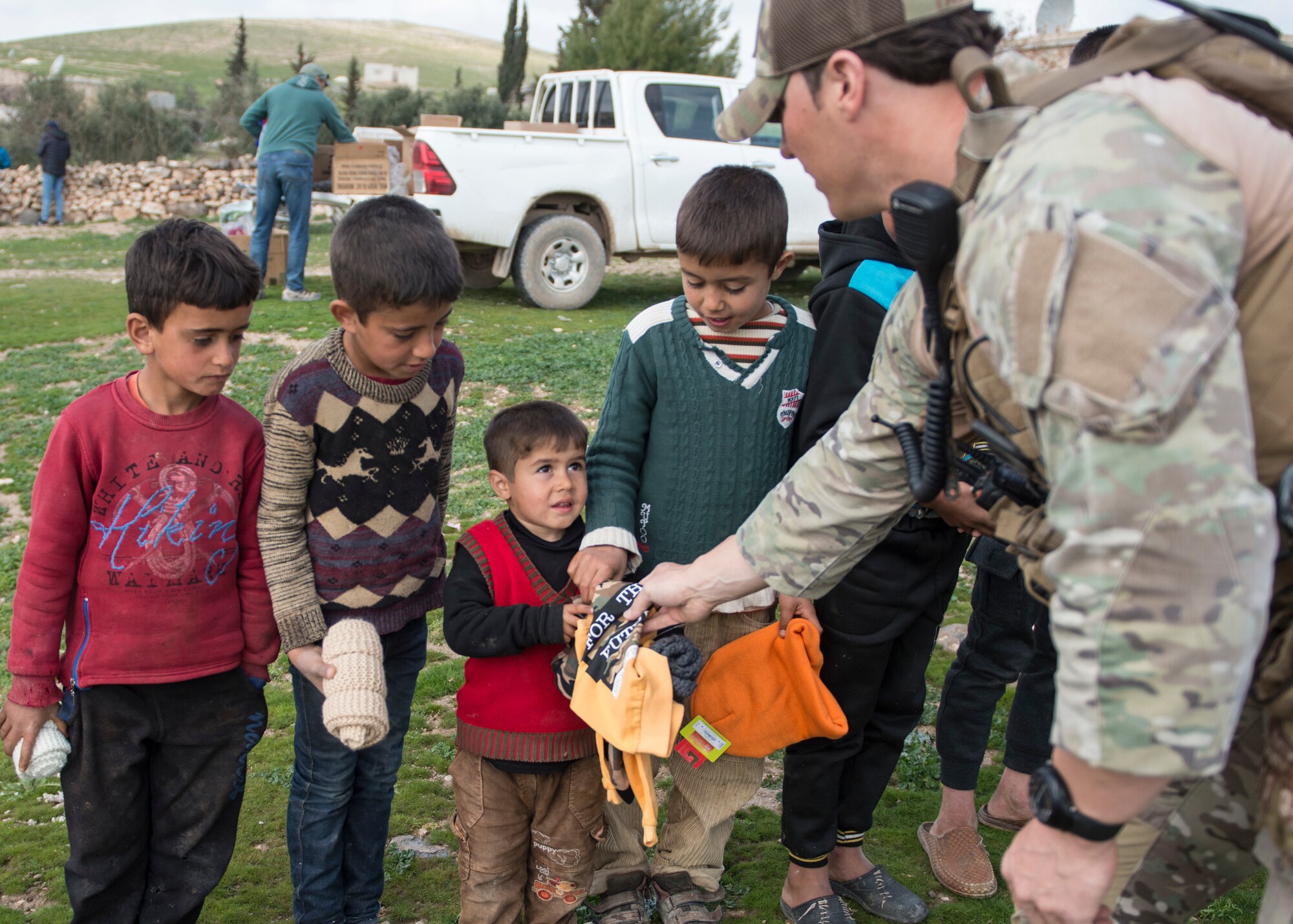 Tech Sgt. Brian Taylor, 441st Air Expeditionary Squadron EOD team leader hands a little boy a shirt March 12, 2019, Southwest Asia. Families in the area have gone without essential items due to the violent conflicts in the area. (U.S. Air Force photo by Staff Sgt. Malissa Armstrong)