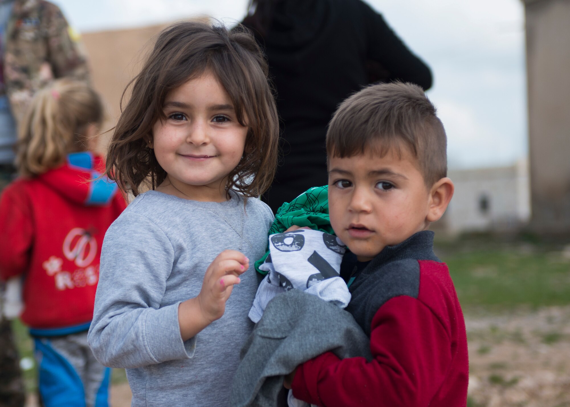 A little girl and her brother smile for a photo after receiving new clothes March 12, 2019, Southwest Asia. Most of the children in the area wear the same items over and over and don't know when they'll get new clothing. (U.S. Air Force photo by Staff Sgt. Malissa Armstrong)