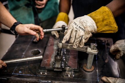 Norfolk Naval Shipyard's Subject Matter Expert Welding Instructor Lamont Smith clamps down the flat bar onto two test plates.