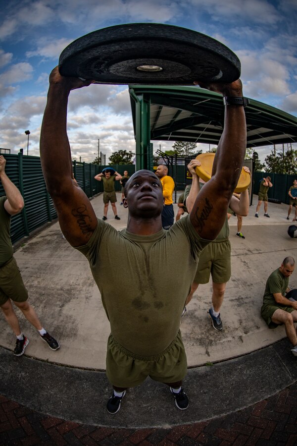A Marine with Marine Forces Reserve lifts a weighted plate at Marine Corps Support Facility New Orleans, March 29, 2019, during a Total Force Fitness event. The MARFORRES Marines conducted various physical activities, such as tug-of-war, buddy carries, high-intensity suicide drills, medicine ball exercises and the dissemble and assembly of a M4 Service Carbine. The event promoted physical fitness, unit cohesion and esprit de corps. (U.S. Marine Corps photo by Sgt. Andy O. Martinez)