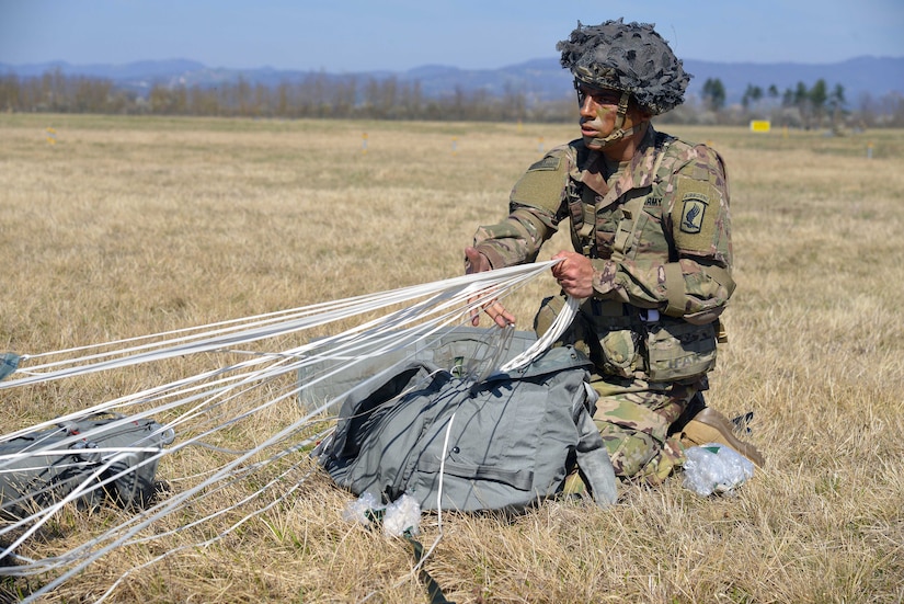 A paratrooper secures his equipment after a jump.
