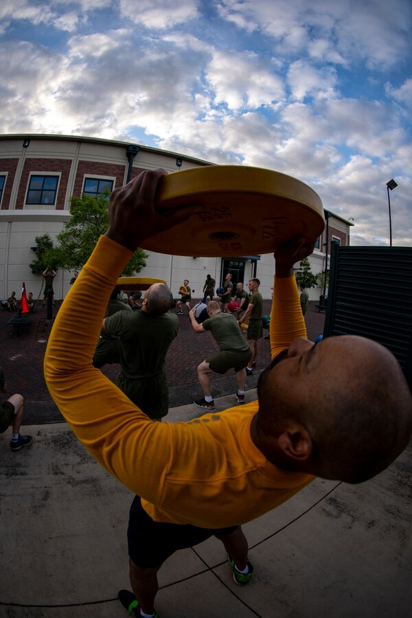 A Sailor with Marine Forces Reserve lifts a weighted plate at Marine Corps Support Facility New Orleans, March 29, 2019, during a Total Force Fitness event. The MARFORRES Marines conducted various physical activities, such as tug-of-war, buddy carries, high-intensity suicide drills, medicine ball exercises and the dissemble and assembly of a M4 Service Carbine. The event promoted physical fitness, unit cohesion and esprit de corps. (U.S. Marine Corps photo by Sgt. Andy O. Martinez)