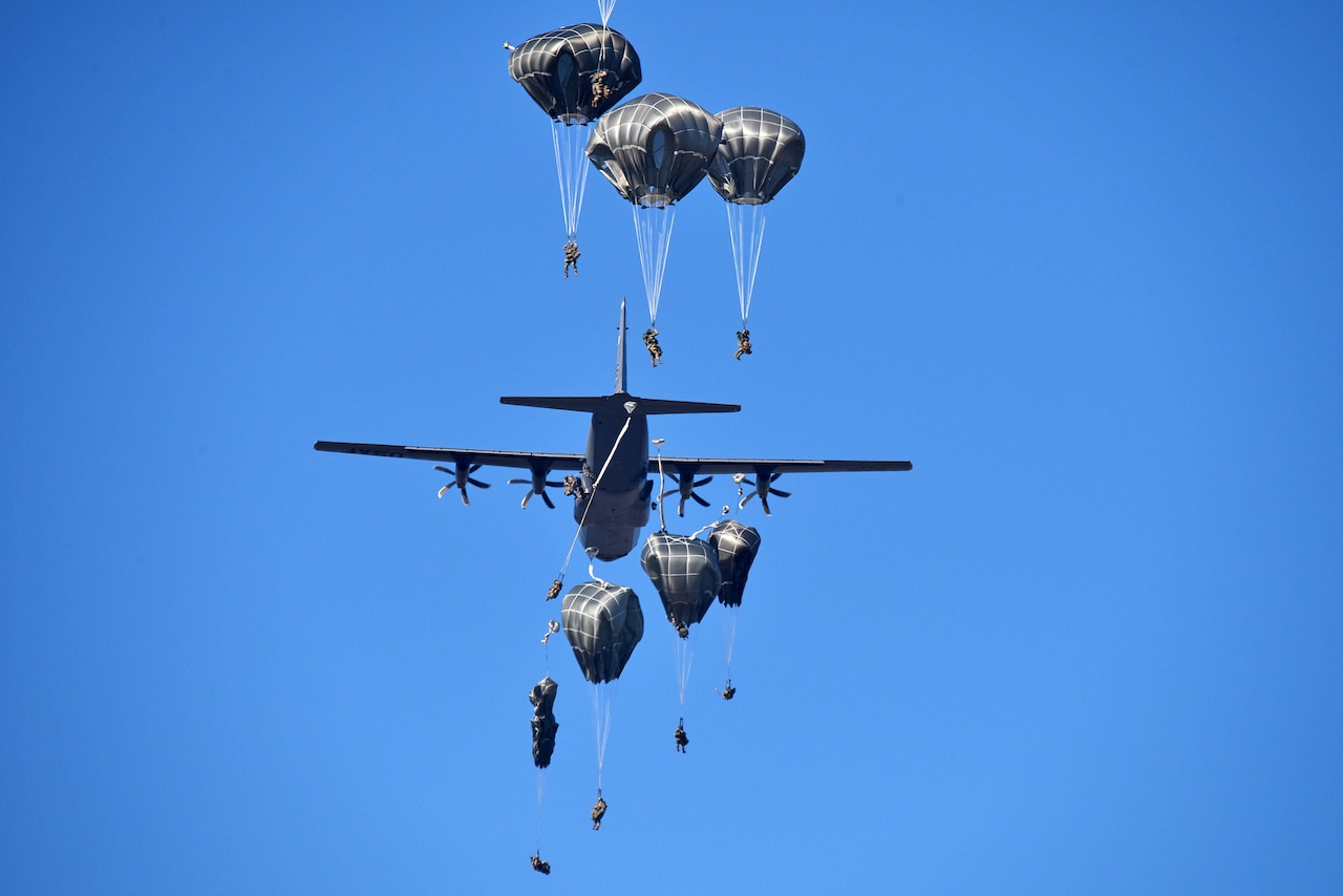 Soldiers jump from a plane.