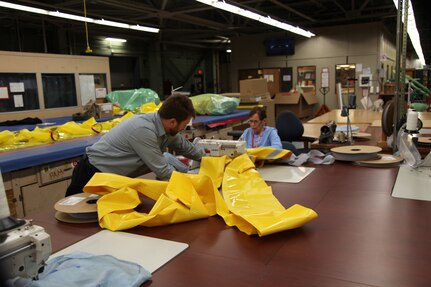 Norfolk Naval Shipyard's Shop 89’s Zone Manager David Kinnaird assists Fabric Linda Jones sewing
specialized personal protection equipment.