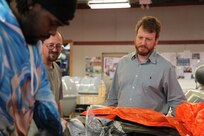 Norfolk Naval Shipyard's Shop 89’s Zone Manager David Kinnaird talks career paths with Fabric Worker Jamie Faulker
and Gregory Stephens as they pack life rafts
for USS George H.W. Bush (CVN 77).