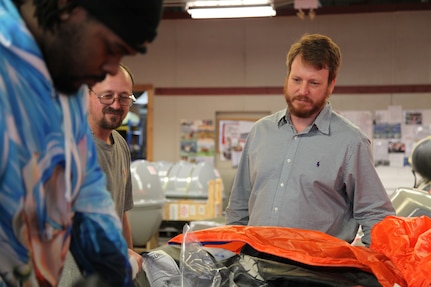 Norfolk Naval Shipyard's Shop 89’s Zone Manager David Kinnaird talks career paths with Fabric Worker Jamie Faulker
and Gregory Stephens as they pack life rafts
for USS George H.W. Bush (CVN 77).